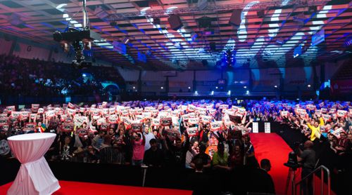 Die Dartfans in Leverkusen halten für die Kamera brav ihre 180er Schilder hoch